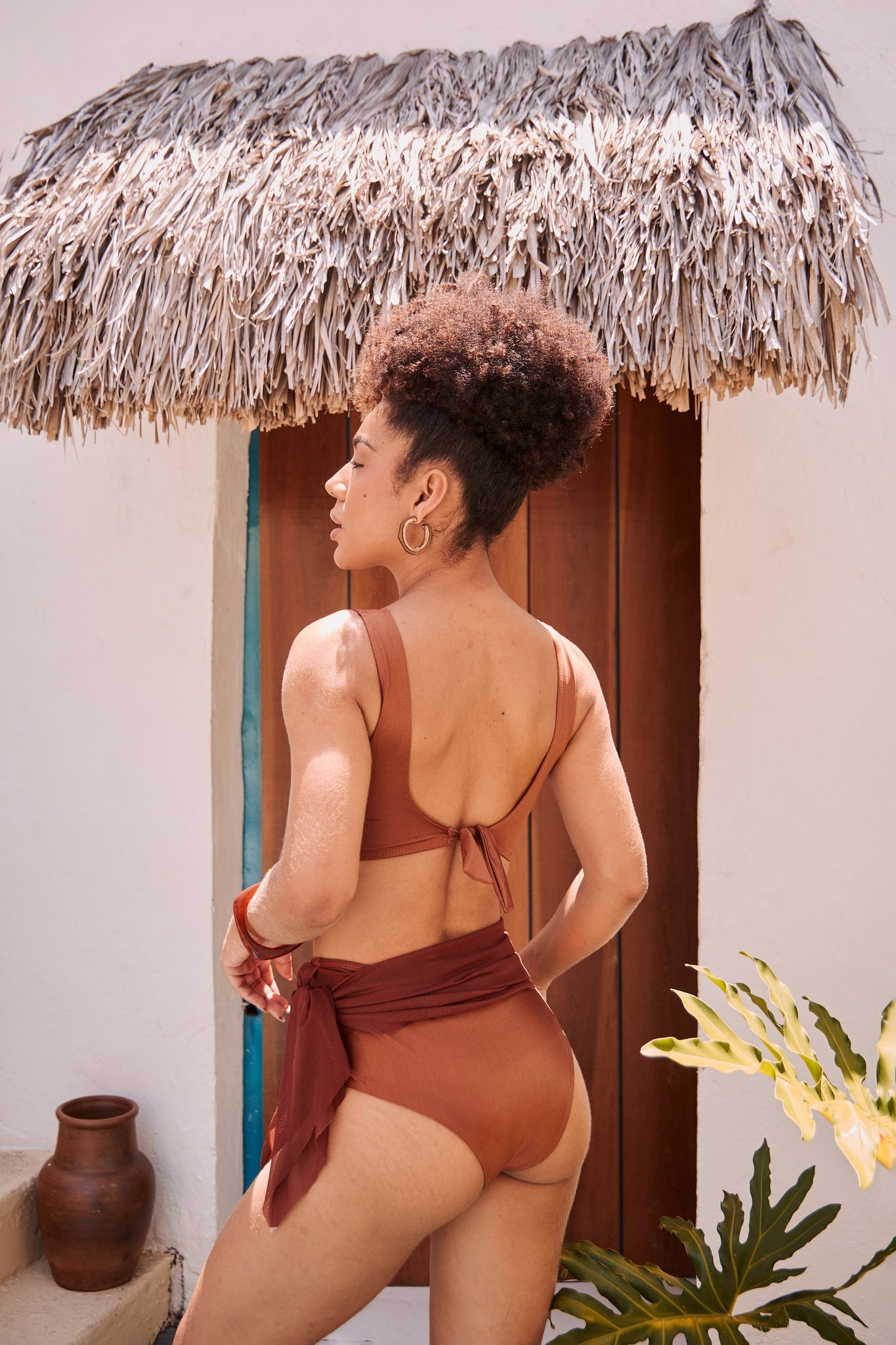 Orixah Suntrail Resort Set in rust, rear view with wrap skirt and tropical plant foreground